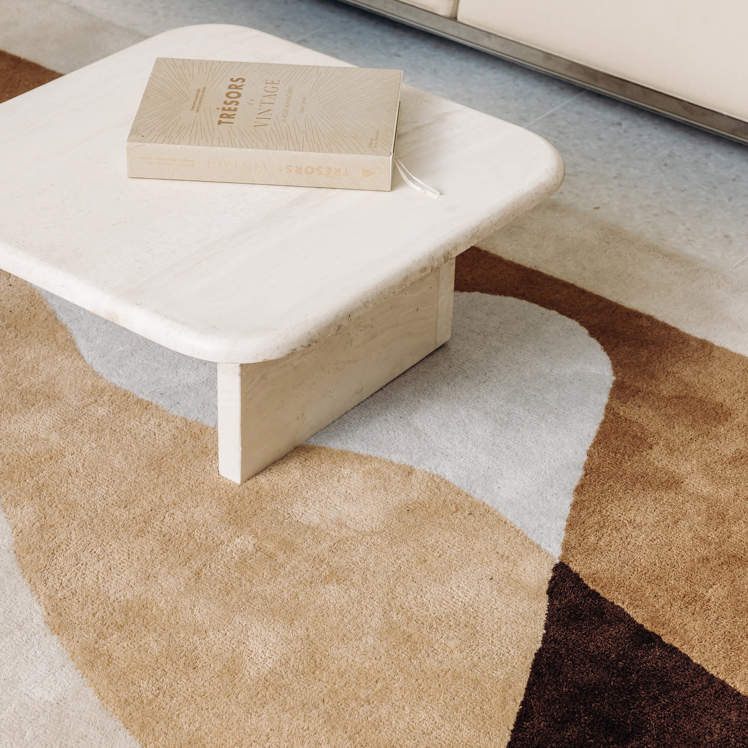 Tapis ocre en laine sous une table basse en travertin