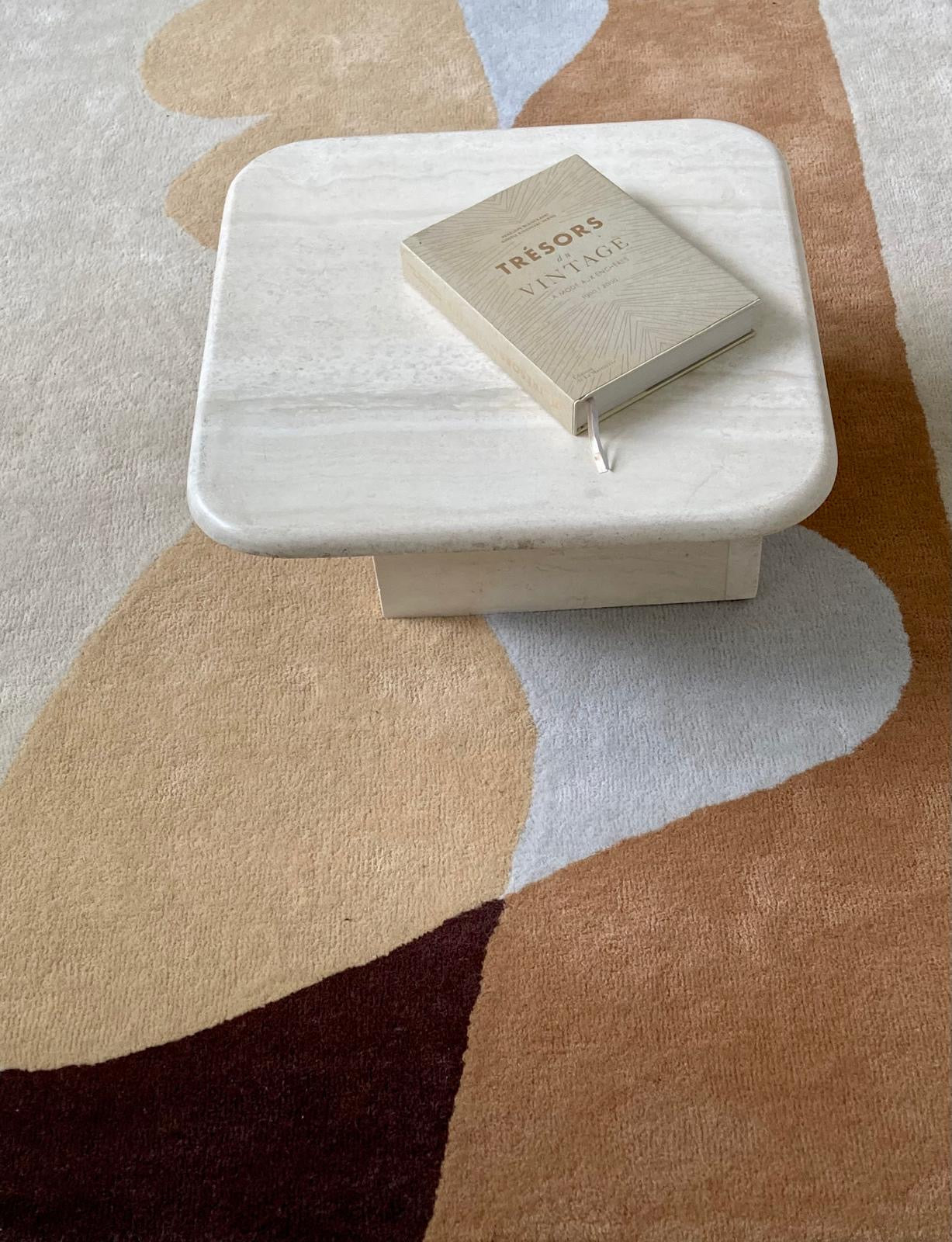 Tapis en laine beige sous table basse travertin